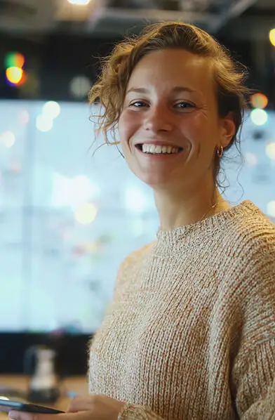 Smiling person holding smartphone indoors